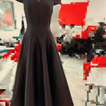 Dark gray dress on a mannequin against a blurred indoor background