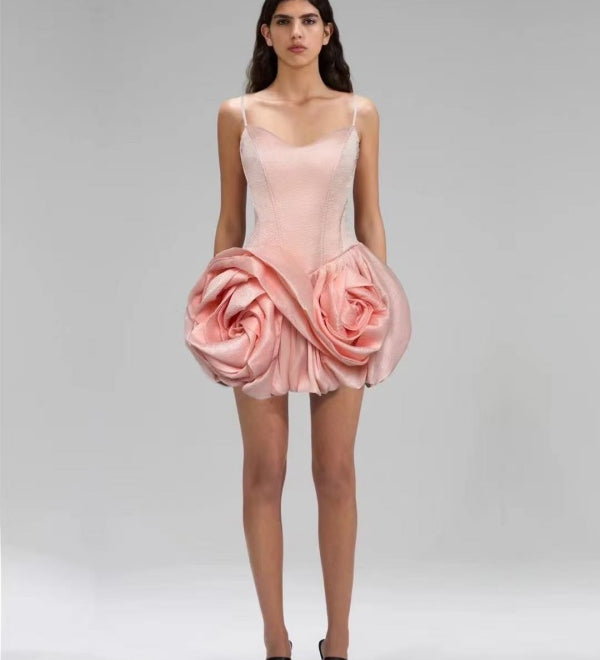 Pink dress with floral design worn by a model on a gray background