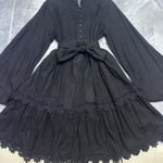 Black dress with lace details on a hanger against a tiled floor background