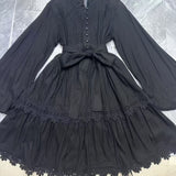 Black dress with lace details on a hanger against a tiled floor background