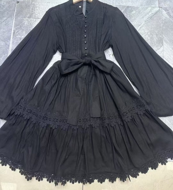 Black dress with lace details on a hanger against a tiled floor background