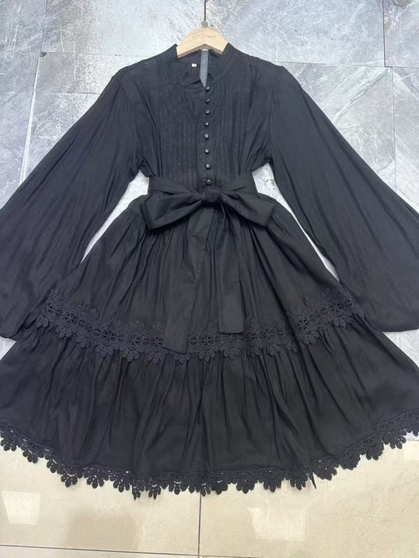 Black dress with lace details on a hanger against a tiled floor background