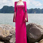 Woman in fuchsia embellished cape gown by the sea