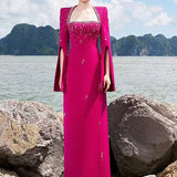 Woman in fuchsia embellished cape gown by the sea