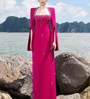 Woman in fuchsia embellished cape gown by the sea
