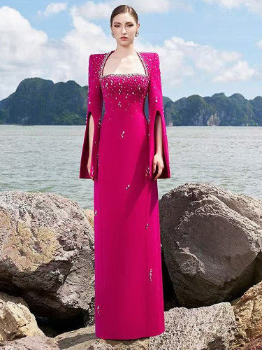 Woman in fuchsia embellished cape gown by the sea