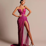 Elegant woman in fuchsia strapless evening gown with deep neckline and high slit, standing in studio setting