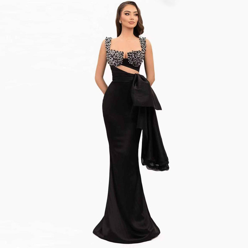 Black crystal-embellished evening gown with square neckline, side bow, and mermaid fit – worn by model in studio – EtiquetteMode formal collection