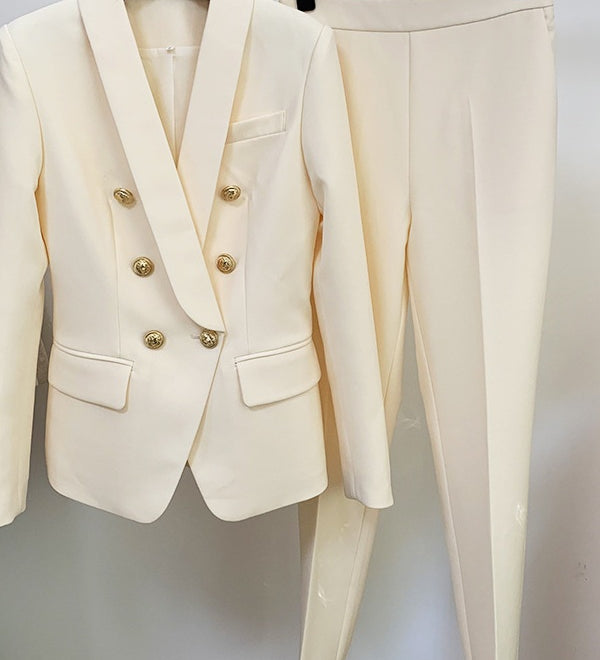 White suit jacket with gold buttons and matching pants on a hanger against a white background