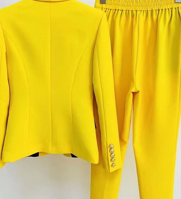 Yellow suit jacket and pants on hangers against a white background