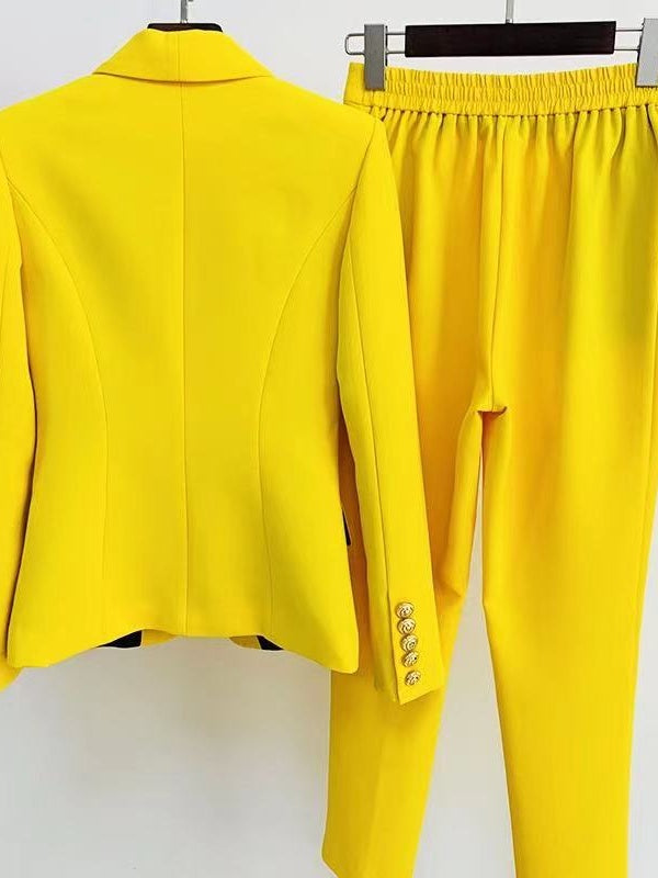 Yellow suit jacket and pants on hangers against a white background