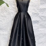 Black evening gown on a mannequin against a textured white background
