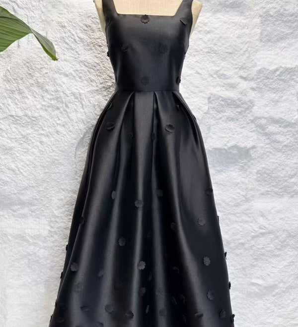 Black evening gown on a mannequin against a textured white background