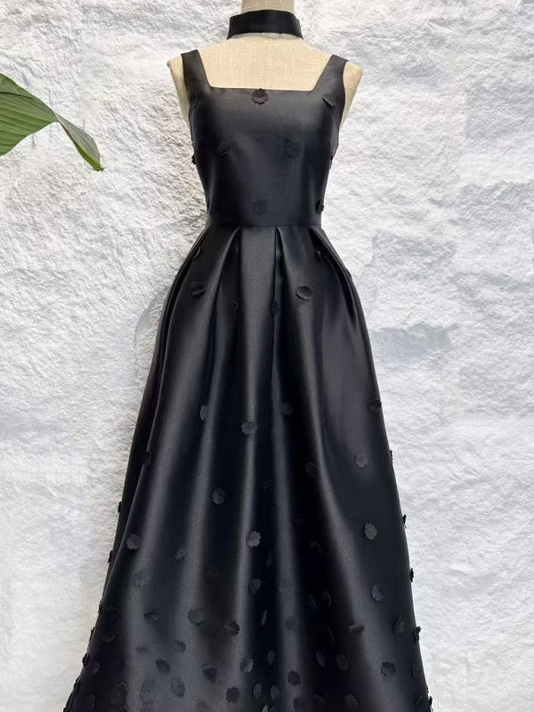 Black evening gown on a mannequin against a textured white background